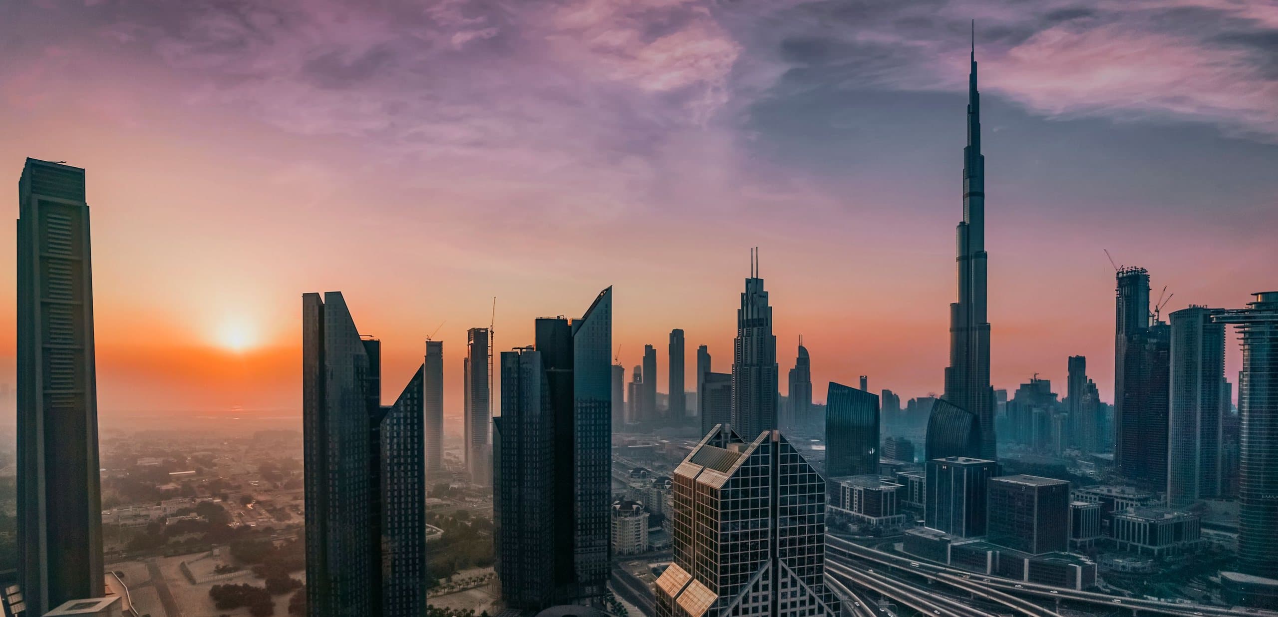 Dubai's Downtown skyline at sunrise, with the Burj Khalifa rising over Sheikh Zayed Road.